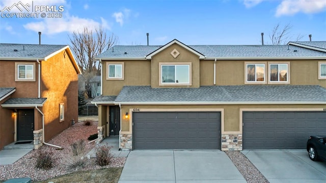 view of front of property featuring a garage, stone siding, driveway, and stucco siding