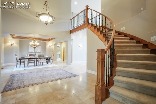 tiled foyer entrance with baseboards, a high ceiling, arched walkways, and stairs