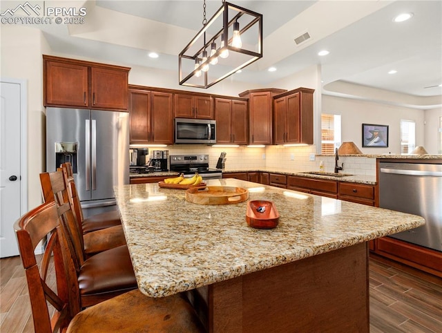 kitchen featuring appliances with stainless steel finishes, a tray ceiling, wood finish floors, and decorative backsplash