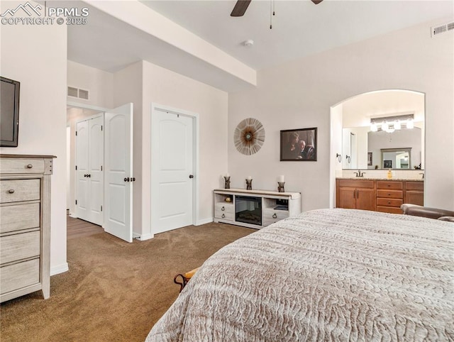 bedroom with arched walkways, carpet, visible vents, and baseboards