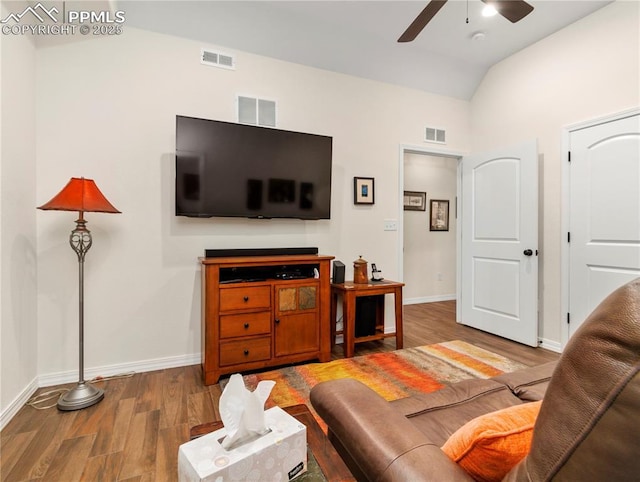 living area featuring vaulted ceiling, wood finished floors, and visible vents