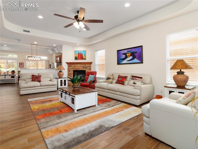 living room with recessed lighting, wood finish floors, a fireplace, visible vents, and a raised ceiling