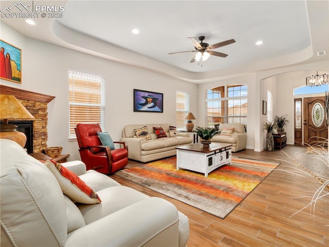 living area featuring recessed lighting, a raised ceiling, a fireplace, and light wood finished floors