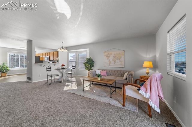 living area featuring visible vents, baseboards, an inviting chandelier, carpet, and a textured ceiling