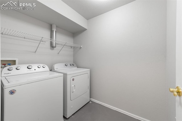 clothes washing area with laundry area, baseboards, and washer and dryer