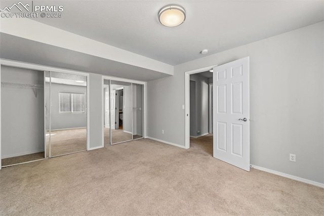 unfurnished bedroom featuring baseboards, carpet, and multiple closets