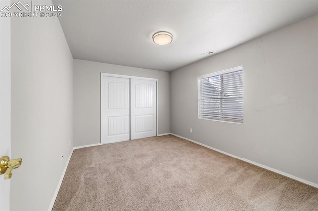 unfurnished bedroom with baseboards, a closet, visible vents, and carpet flooring