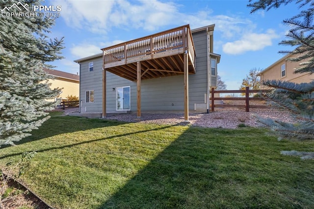 rear view of house featuring a yard, a deck, and fence