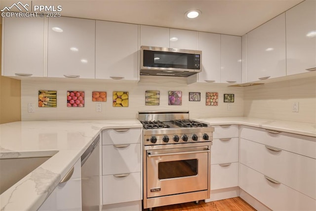 kitchen featuring appliances with stainless steel finishes, white cabinetry, light stone counters, and modern cabinets