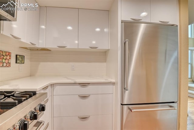 kitchen with light stone countertops, stainless steel fridge, modern cabinets, and white cabinetry