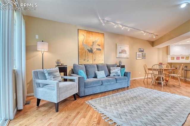 living room with visible vents, track lighting, baseboards, and wood finished floors