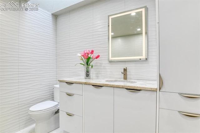 bathroom featuring tile walls, toilet, and vanity