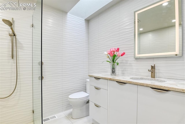 full bathroom featuring tile walls, visible vents, toilet, vanity, and walk in shower