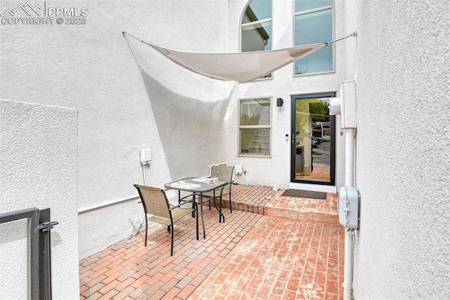 view of exterior entry with a patio area, outdoor dining area, and stucco siding