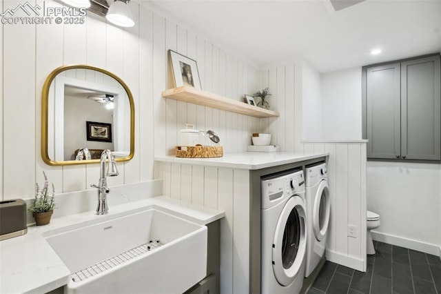 laundry room featuring independent washer and dryer, dark tile patterned floors, ceiling fan, and baseboards
