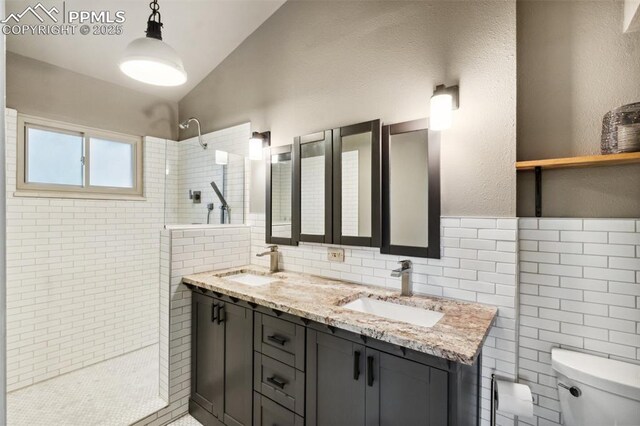bathroom featuring a walk in shower, toilet, tile walls, double vanity, and a textured wall