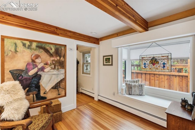 living area with light wood-style floors, beamed ceiling, and a baseboard heating unit