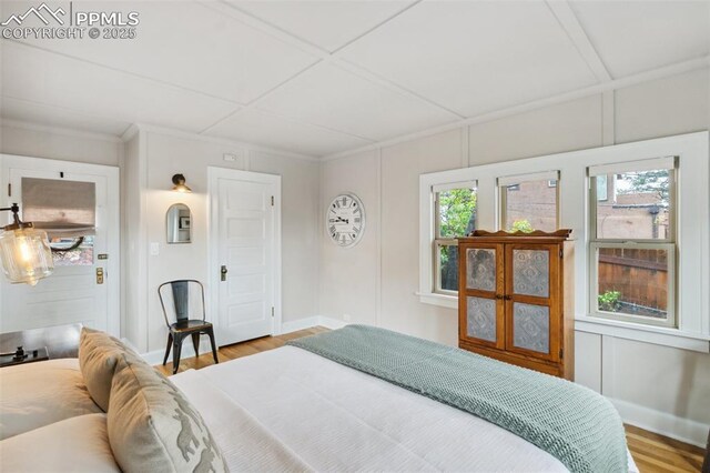 bedroom featuring wood finished floors, baseboards, and crown molding