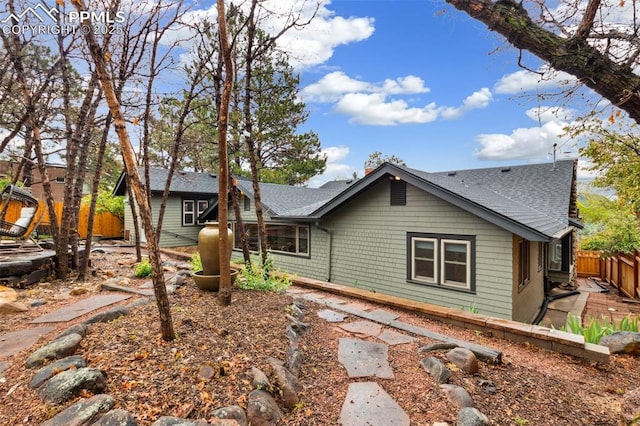 view of front of property featuring roof with shingles and fence