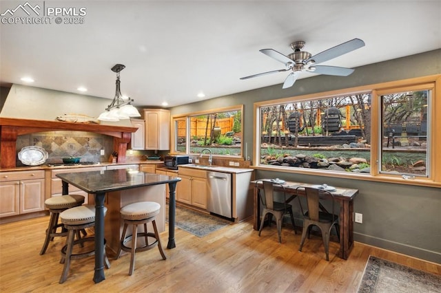 kitchen with dishwasher, light brown cabinets, a sink, a kitchen breakfast bar, and recessed lighting