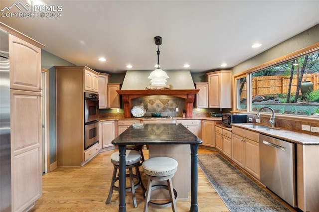 kitchen with stainless steel dishwasher, a sink, premium range hood, multiple ovens, and light brown cabinetry