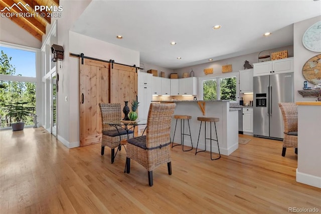 kitchen with high quality fridge, a barn door, light wood-style flooring, and white cabinets