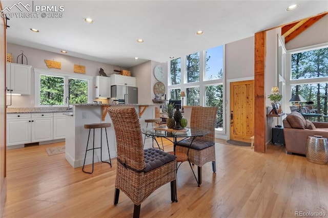 dining room with light wood-style floors, recessed lighting, and a towering ceiling