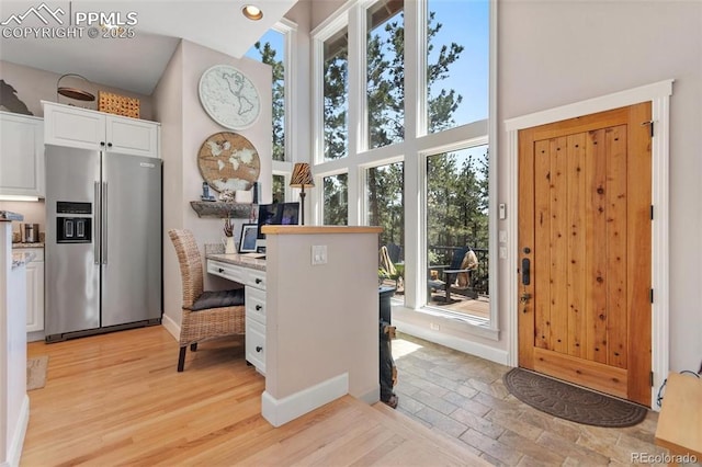 interior space featuring light wood-type flooring, a towering ceiling, and baseboards