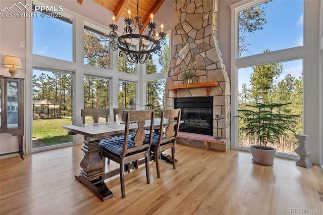 sunroom with lofted ceiling, wood ceiling, a notable chandelier, and a stone fireplace