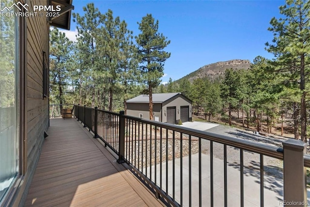 deck featuring an outdoor structure, a detached garage, and a mountain view