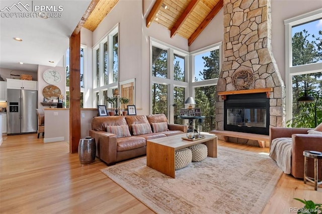 sunroom with a healthy amount of sunlight, wooden ceiling, lofted ceiling with beams, and a stone fireplace