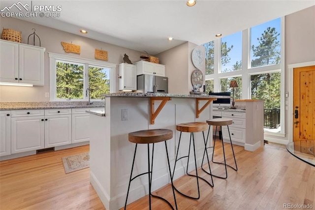 kitchen featuring light wood-type flooring, a center island, white cabinetry, and freestanding refrigerator