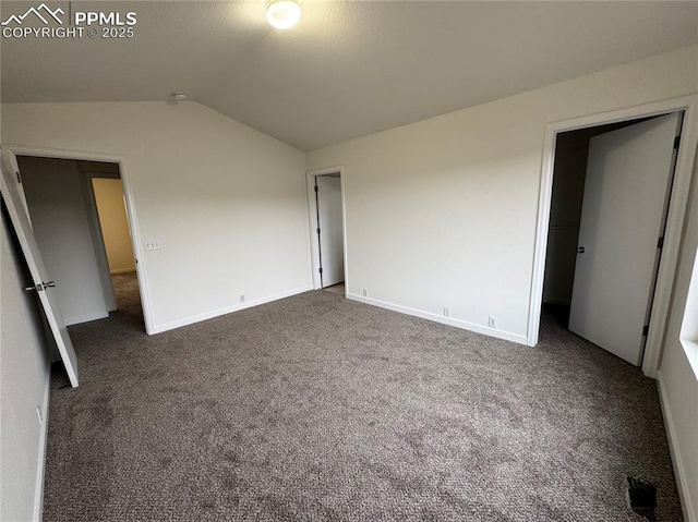 unfurnished bedroom with lofted ceiling, baseboards, and dark colored carpet