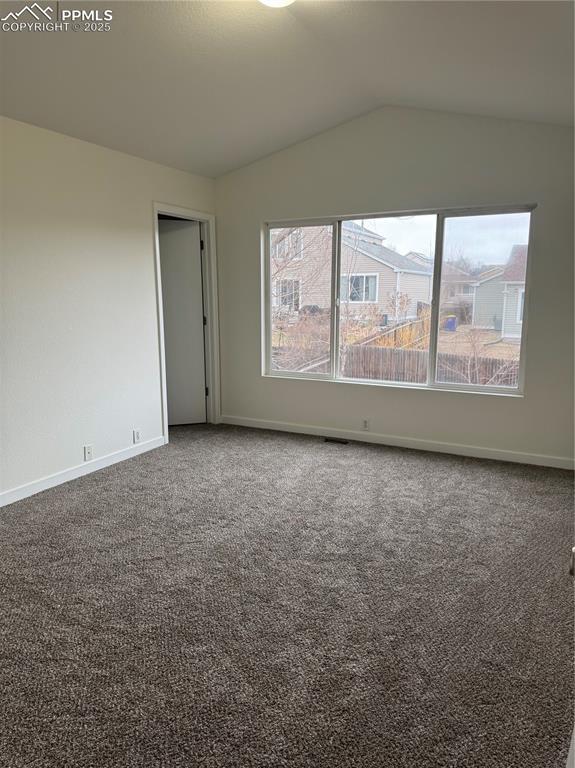 carpeted empty room with vaulted ceiling and baseboards