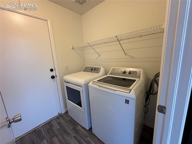 clothes washing area featuring dark wood-type flooring, laundry area, and washer and clothes dryer