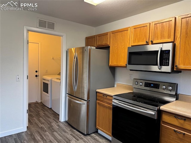 kitchen with appliances with stainless steel finishes, light countertops, visible vents, and separate washer and dryer