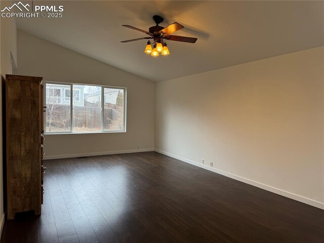 empty room featuring lofted ceiling, ceiling fan, baseboards, and dark wood-style flooring