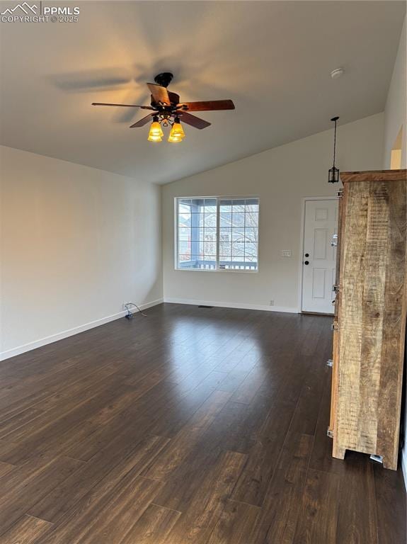 spare room with lofted ceiling, dark wood-type flooring, and baseboards