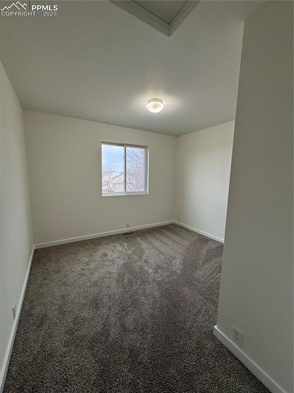 empty room featuring baseboards and dark carpet