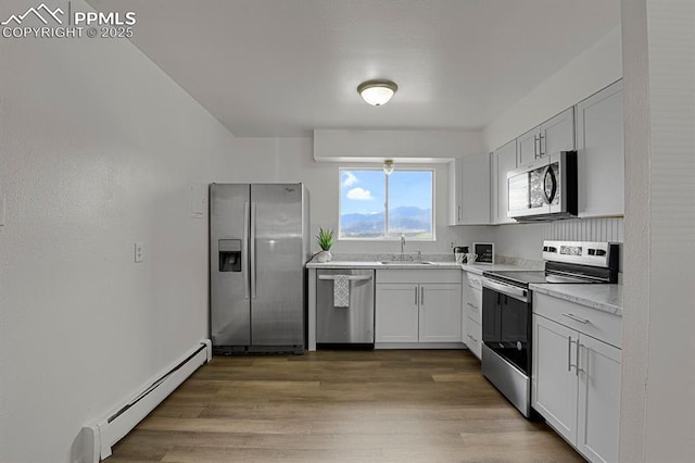 1073 Westmoreland Rd, Colorado Springs, CO 80907 - kitchen with stainless steel appliances, light countertops, light wood-type flooring, a baseboard heating unit, and a sink