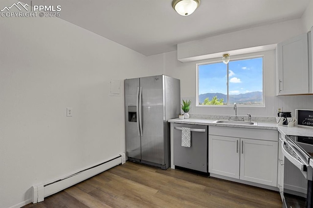 1073 Westmoreland Rd, Colorado Springs, CO 80907 - kitchen with stainless steel appliances, light countertops, baseboard heating, a sink, and light wood-type flooring
