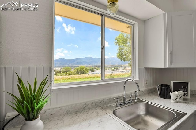 1073 Westmoreland Rd, Colorado Springs, CO 80907 - kitchen with white cabinetry, a mountain view, light stone counters, and a sink