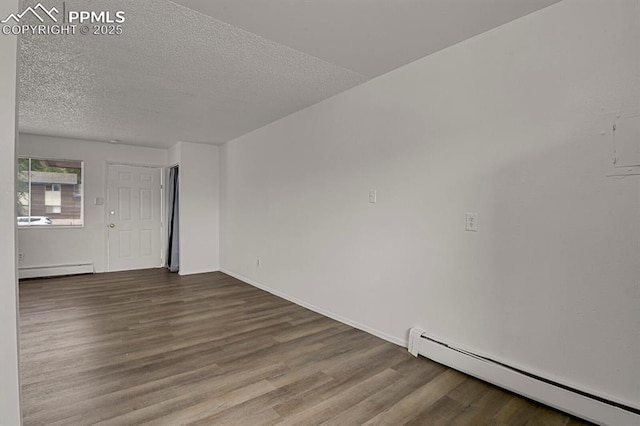 1073 Westmoreland Rd, Colorado Springs, CO 80907 - empty room featuring a textured ceiling, a baseboard heating unit, and wood finished floors
