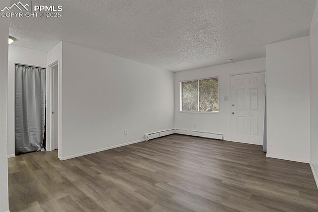 1073 Westmoreland Rd, Colorado Springs, CO 80907 - interior space with baseboards, a baseboard heating unit, dark wood finished floors, and a textured ceiling