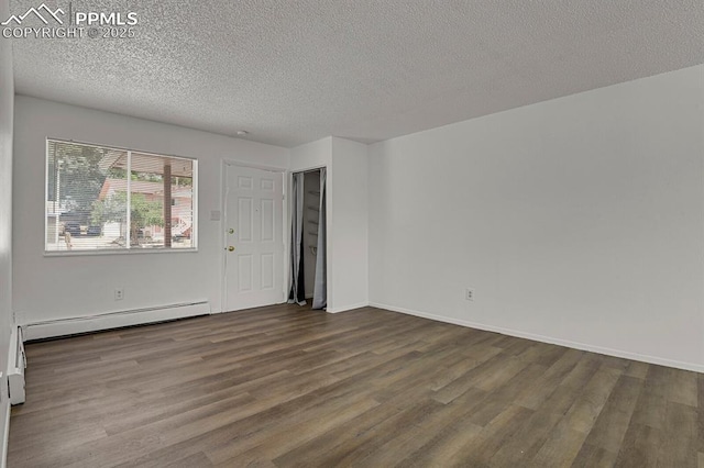 1073 Westmoreland Rd, Colorado Springs, CO 80907 - unfurnished room with a textured ceiling, baseboards, baseboard heating, and dark wood finished floors