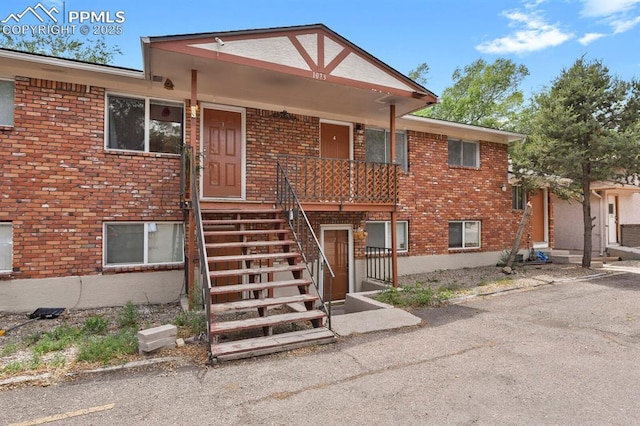 view of front of house featuring covered porch, stairway, and brick siding