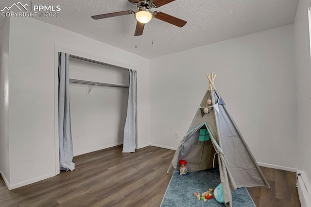 1073 Westmoreland Rd, Colorado Springs, CO 80907 - playroom with a textured ceiling, baseboard heating, wood finished floors, and baseboards