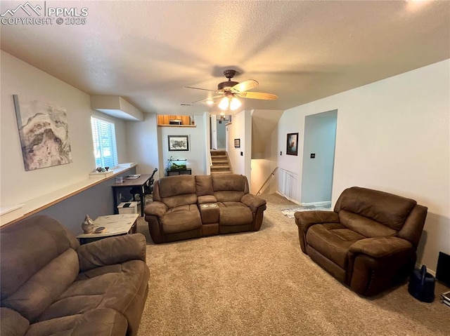 carpeted living room featuring ceiling fan, stairs, and a textured ceiling