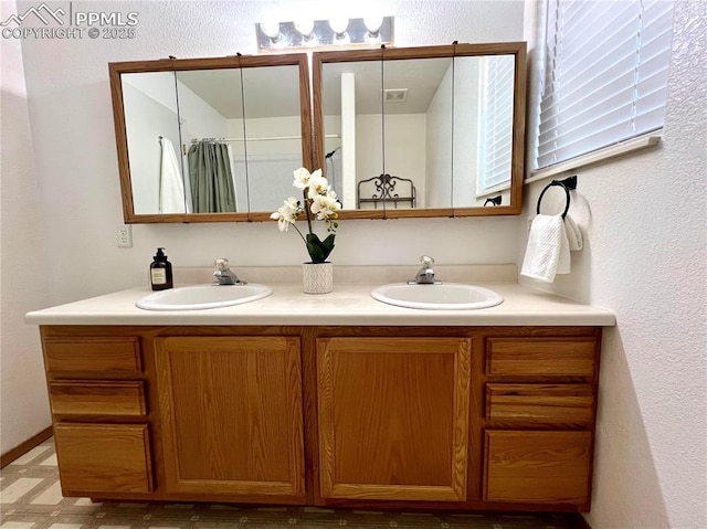 bathroom with double vanity, a sink, and visible vents