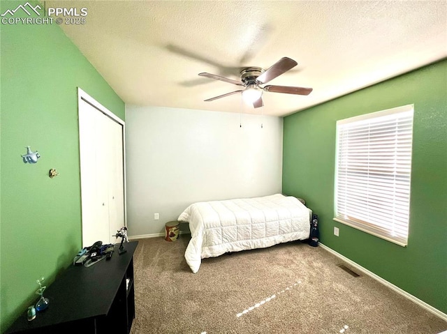 carpeted bedroom featuring a textured ceiling, a ceiling fan, visible vents, baseboards, and a closet